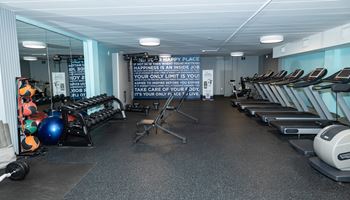 a large fitness room with cardio equipment and a motivational quote on the wall
